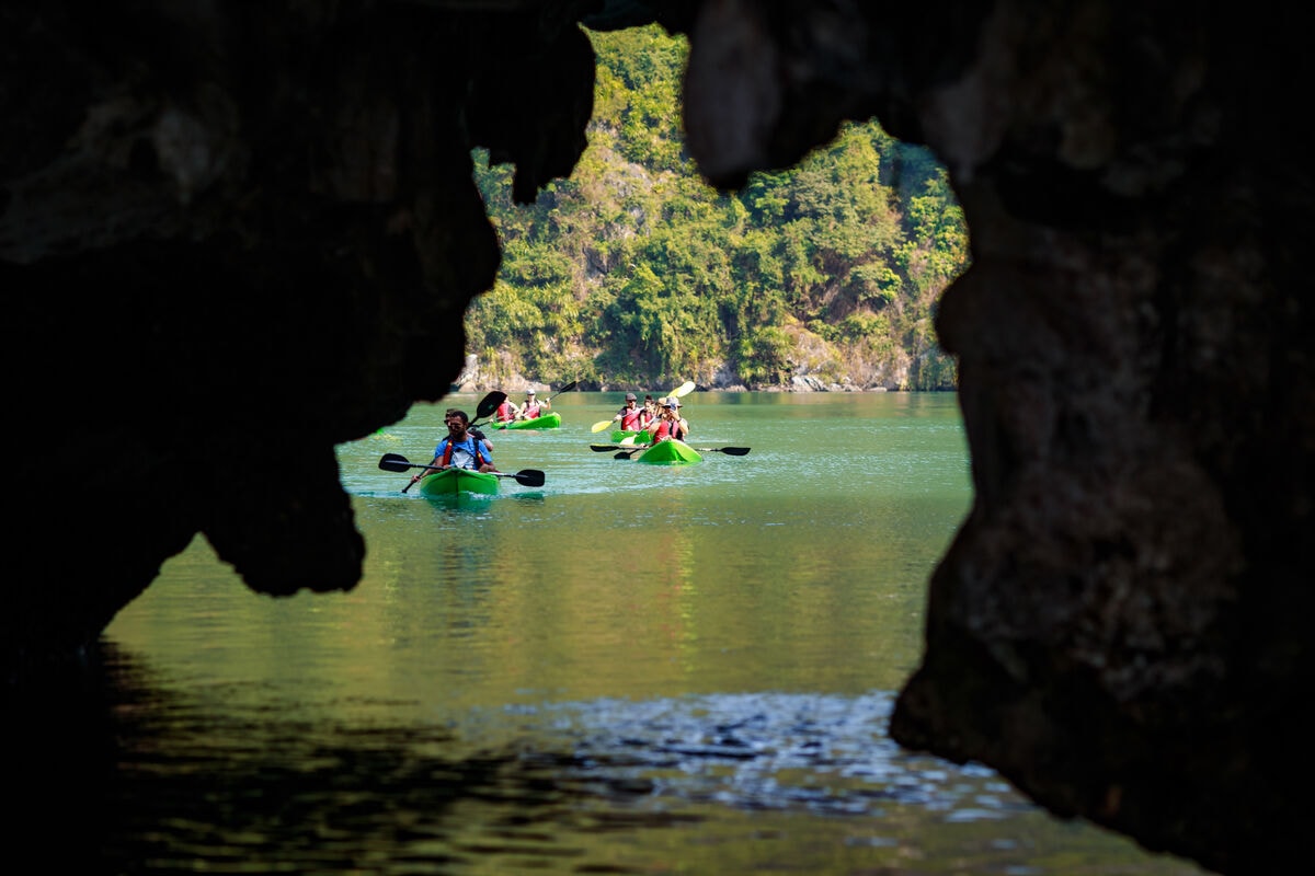 Kayakers framed inside the mouth of a sea cave in Lan Ha Bay