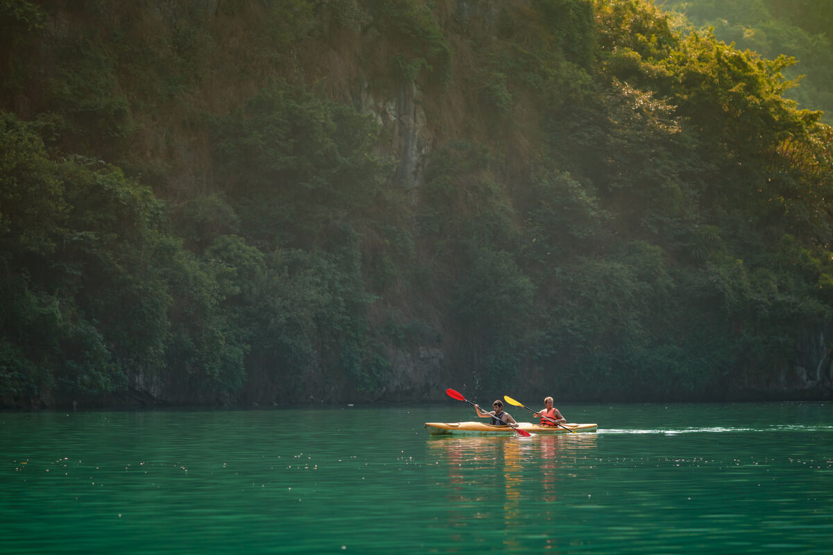 Two-person kayak at golden hour against a Lan Ha Bay cliff